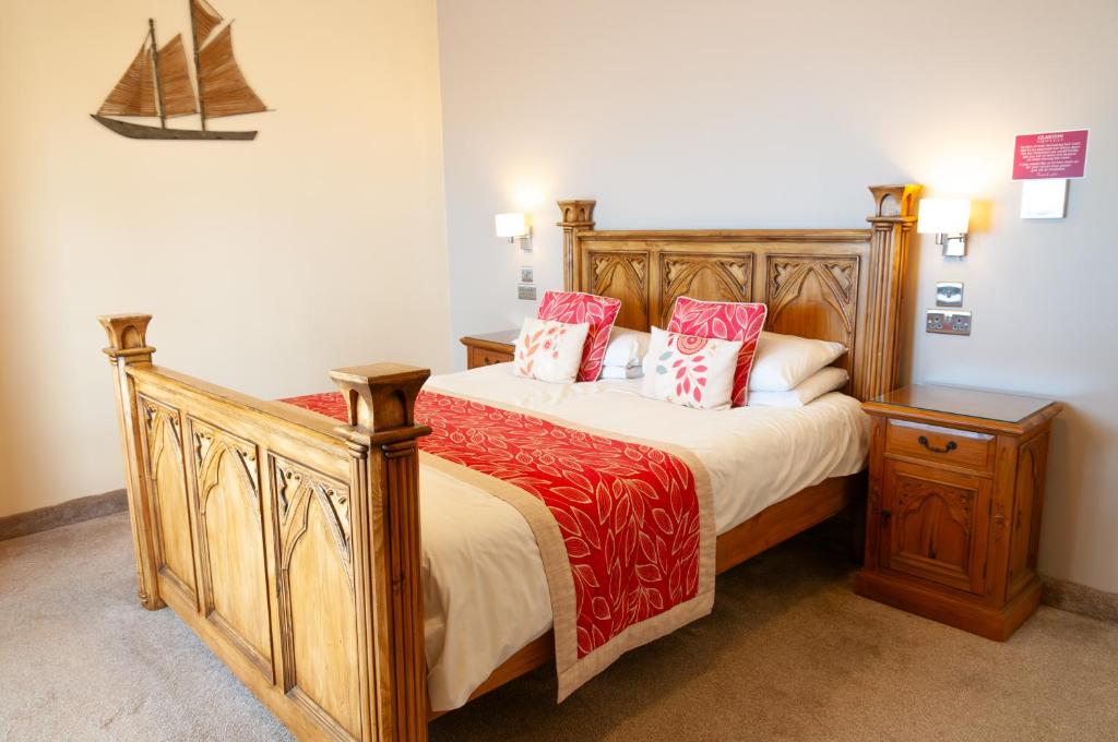 a bedroom with a bed with red and white pillows at Claxton Hotel in Redcar