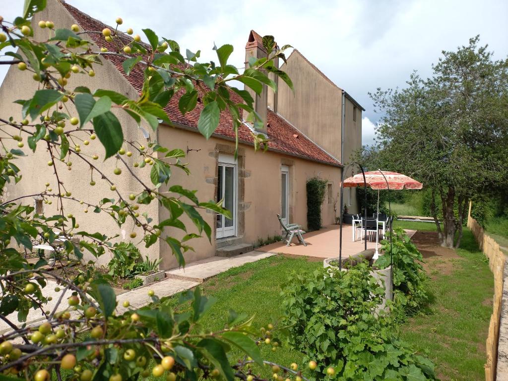 - un jardin avec une maison et un parasol dans l'établissement Gîte Au Val d'Auxois, à Athie