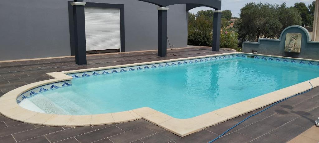 une grande piscine avec de l'eau bleue dans une cour dans l'établissement la Recouturière, à Saint-Thibéry