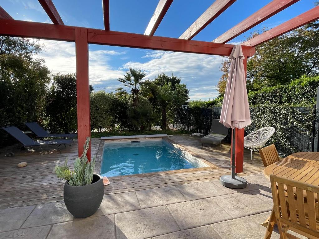 une terrasse avec une piscine, une table et un parasol dans l'établissement Maison avec piscine - Bidart campagne proche plages, à Bidart