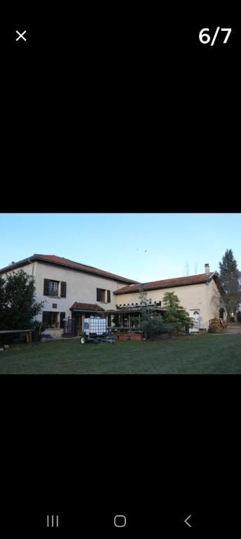 - un grand bâtiment blanc avec une cour devant dans l'établissement Gîtes de la Verne, à Beaurepaire