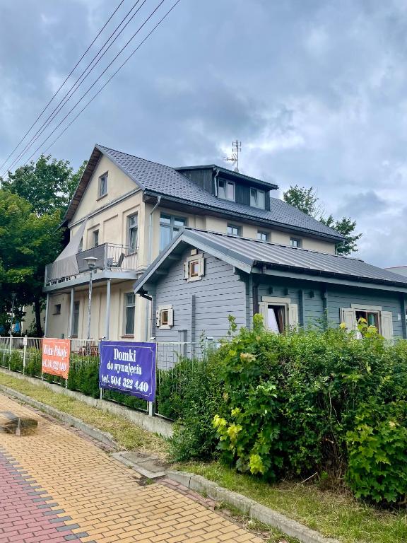 a house with a sign in front of it at Pokoje i domki letniskowe BROS in Dziwnów