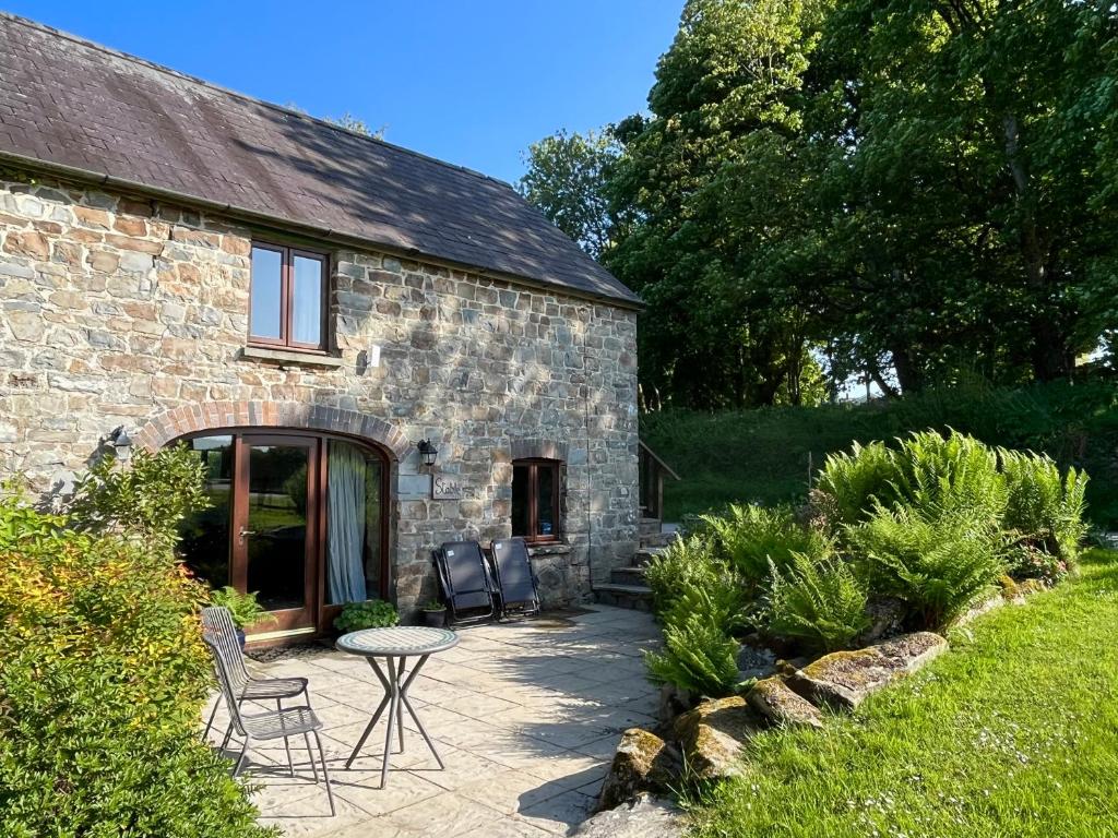 a stone house with a patio and a table and chairs at Stable Cottage in Newport Pembrokeshire