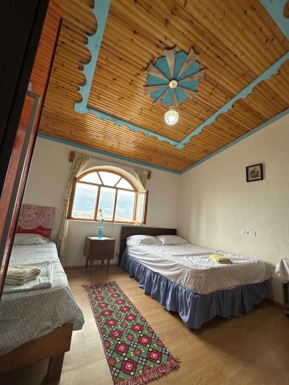 two beds in a room with a wooden ceiling at Villa Zeko in Gjirokastër
