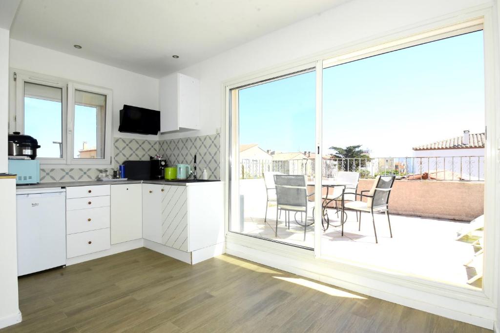a kitchen with white cabinets and a large sliding glass door at les 2 dauphins in Le Barcarès