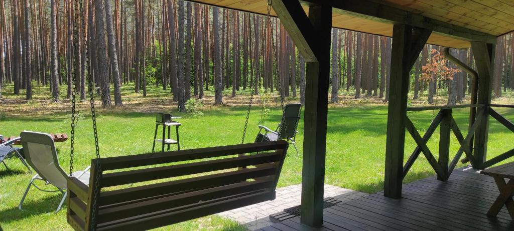 a porch swing with a chair and a table at Domki Nad Tanwią in Susiec
