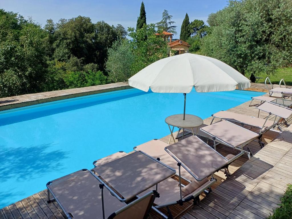 grupa krzeseł i parasol obok basenu w obiekcie Villa Al Ponte w mieście Case Malva