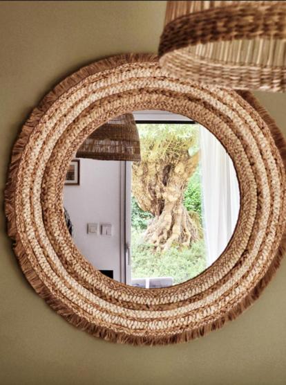 un grand miroir circulaire sur un mur avec une fenêtre dans l'établissement Les oliviers, à Perros-Guirec