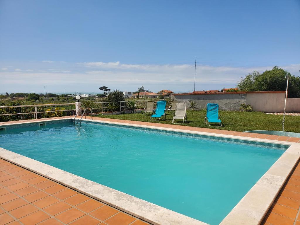 a swimming pool with two blue chairs in a yard at Casamilia Suite Parentale in Esposende