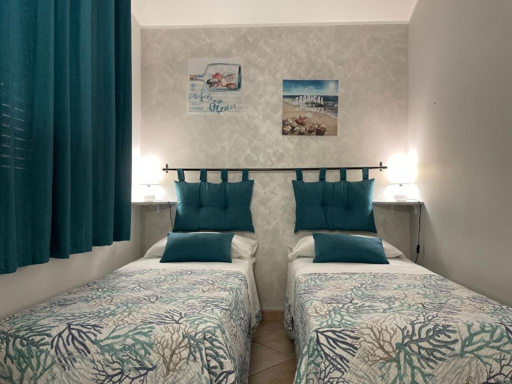 2 łóżka w pokoju z zielonymi zasłonami w obiekcie VILLA ANNA MARIA w mieście Custonaci