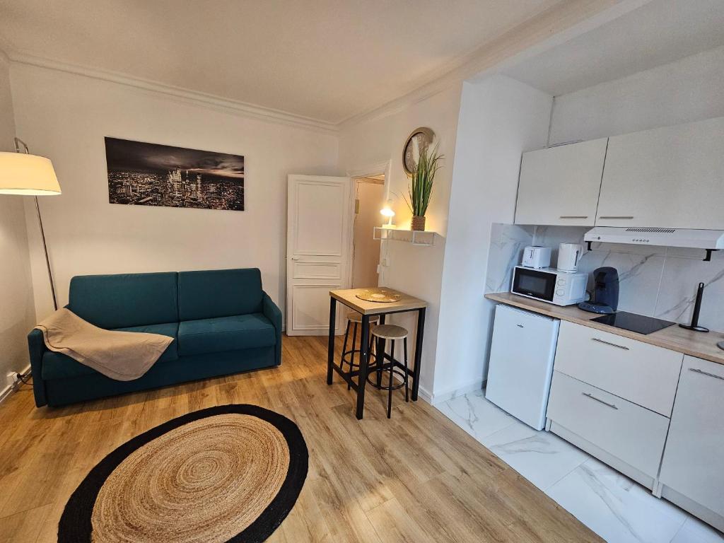 un salon avec un canapé bleu et une cuisine dans l'établissement Appartement a Paris Clichy, à Paris