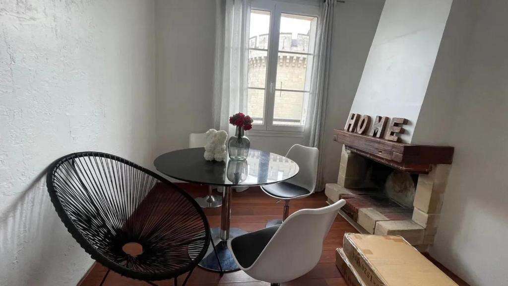 a table and chairs in a room with a fireplace at Appartement spacieux à Caen 65 m² avec balcon vue sur la ville in Caen