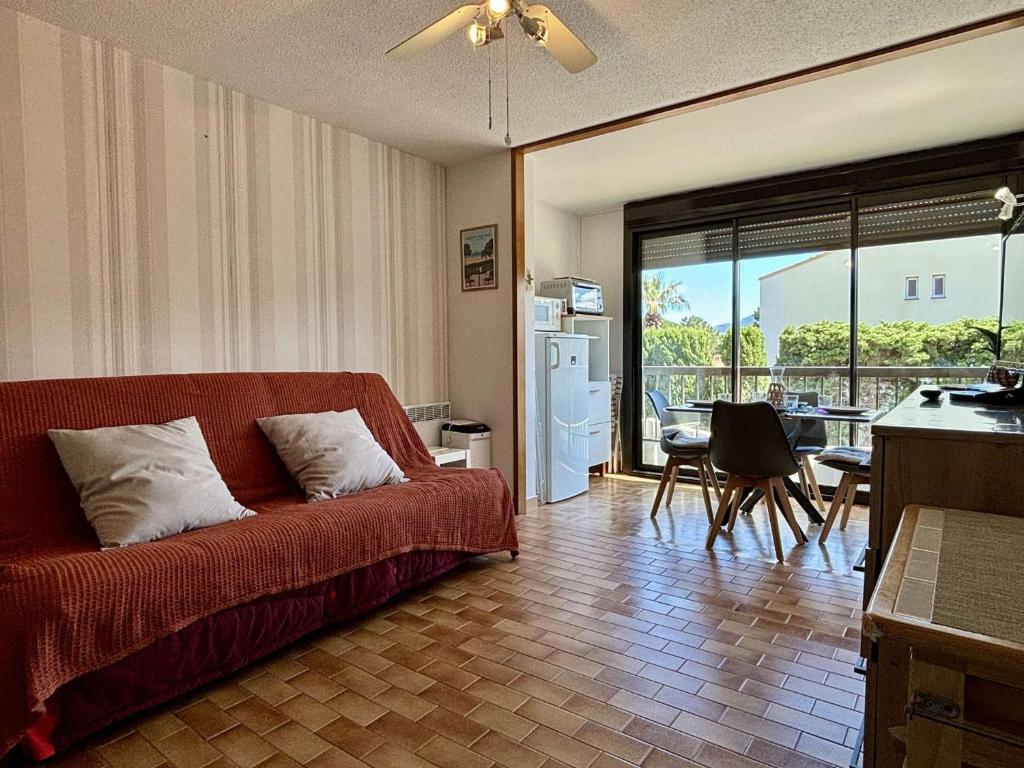un salon avec un canapé rouge et une cuisine dans l'établissement Appartement Studio - cabine 4 couchages ARGELES SUR MER AR030-053, à Argelès-sur-Mer