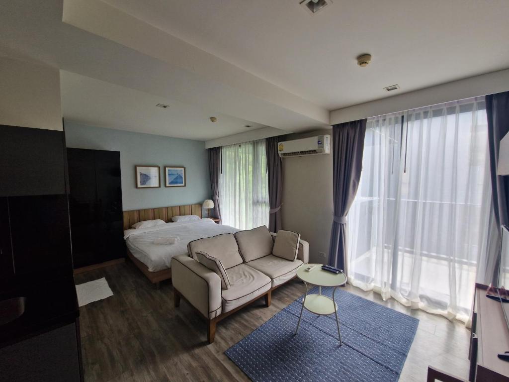 a hotel room with a bed and a couch at The Deck Condo Patong 5Fl Pool View in Patong Beach