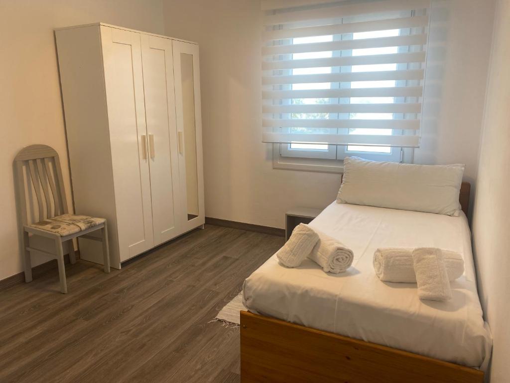 a bedroom with a bed and a chair and a window at Adro Vello in San Vicente de O Grove