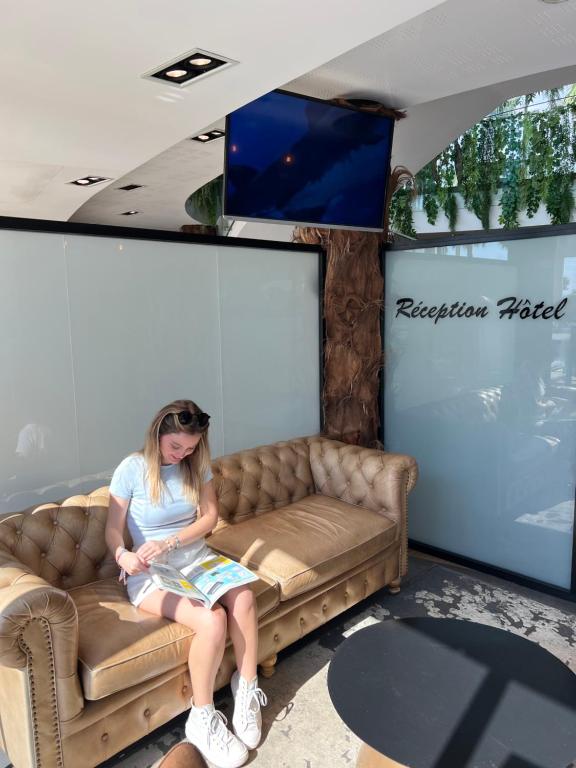 a girl sitting on a couch in a room at SoBlue Hôtel in Antibes