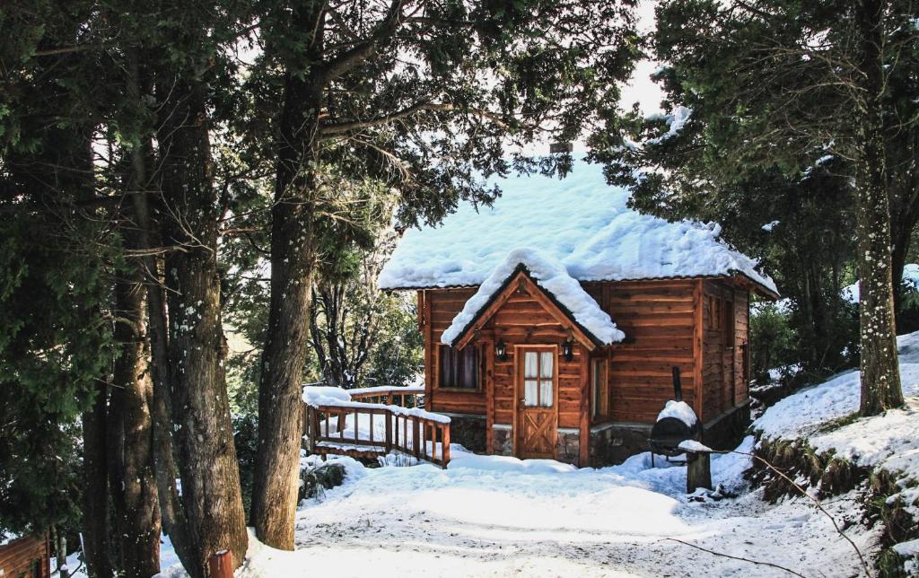 a log cabin with snow on the roof at Cocos Cura Casas de montaña in San Carlos de Bariloche