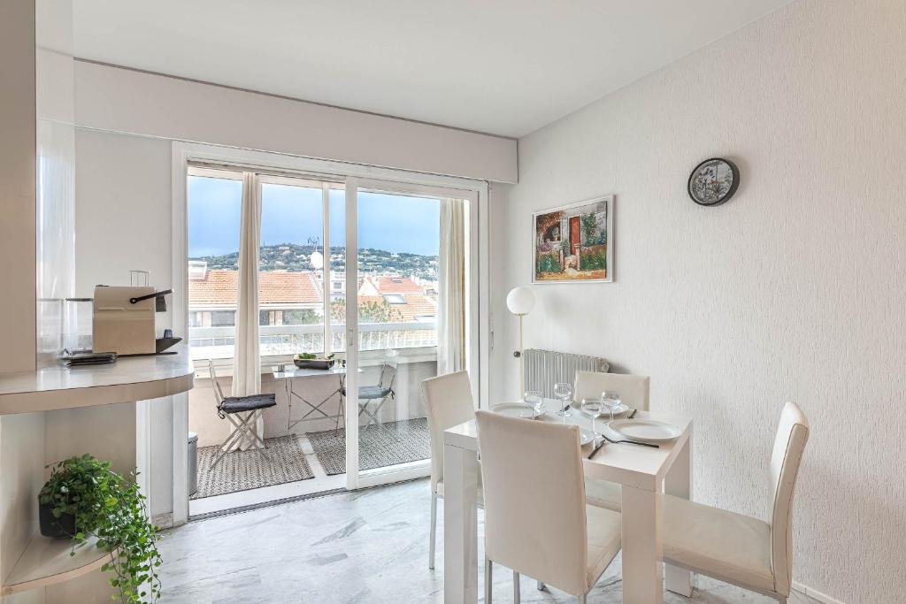 une salle à manger blanche avec une table et une fenêtre dans l'établissement Appartement Cannes Centre Proche de la Croisette!, à Cannes
