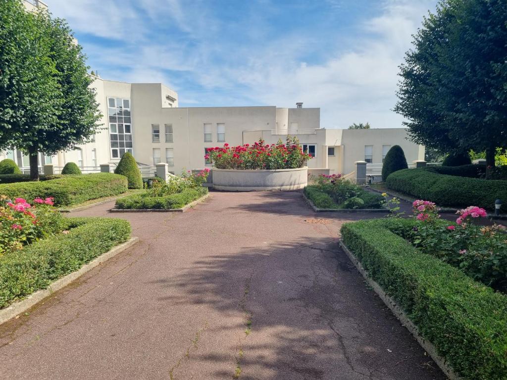 un bâtiment avec un jardin fleuri devant lui dans l'établissement Chambre avec SDB et Toilettes privatives, à Rosny-sous-Bois