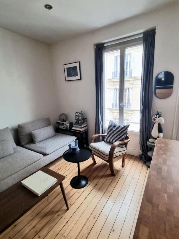 un salon avec un canapé et une chaise dans l'établissement Appartement de charme dans les Batignolles, à Paris