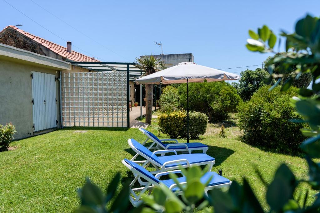 eine Gruppe von Gartenstühlen und einem Regenschirm in der Unterkunft Casa da Praia em Valadares in Vila Nova de Gaia