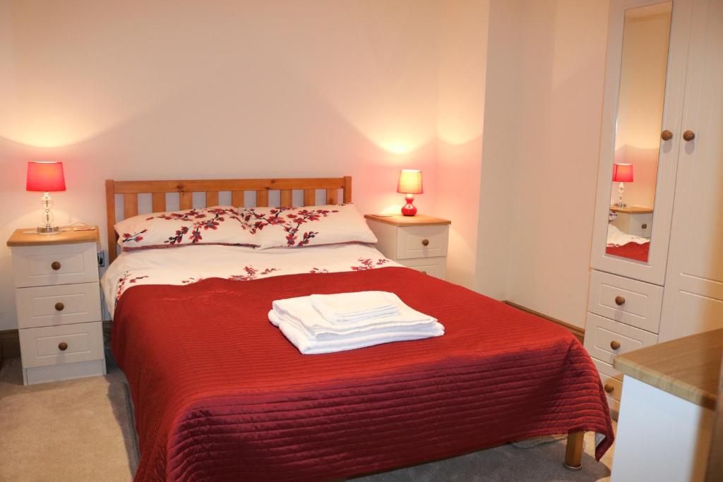 a bedroom with a bed with a red blanket at The Old Chapel, The Cloisters in Gristhorpe