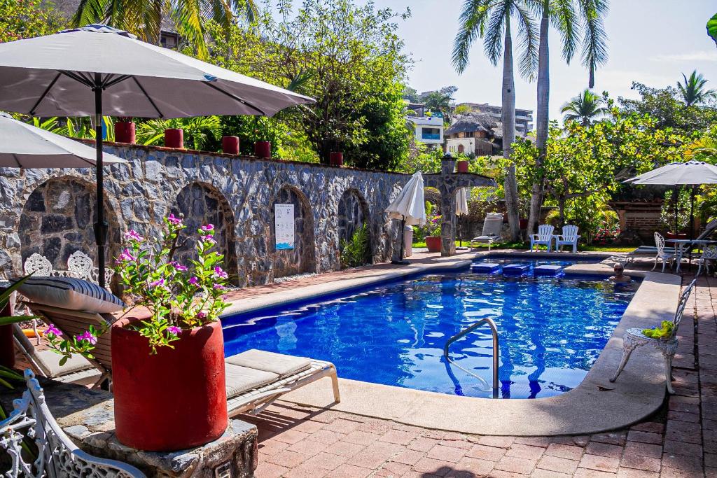 a swimming pool with an umbrella and chairs next to it at Hotel Villas Ema in Zihuatanejo