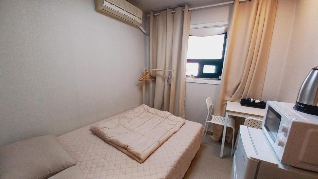 une petite pièce avec un lit et une fenêtre dans l'établissement Sujeongjang Inn, à Séoul