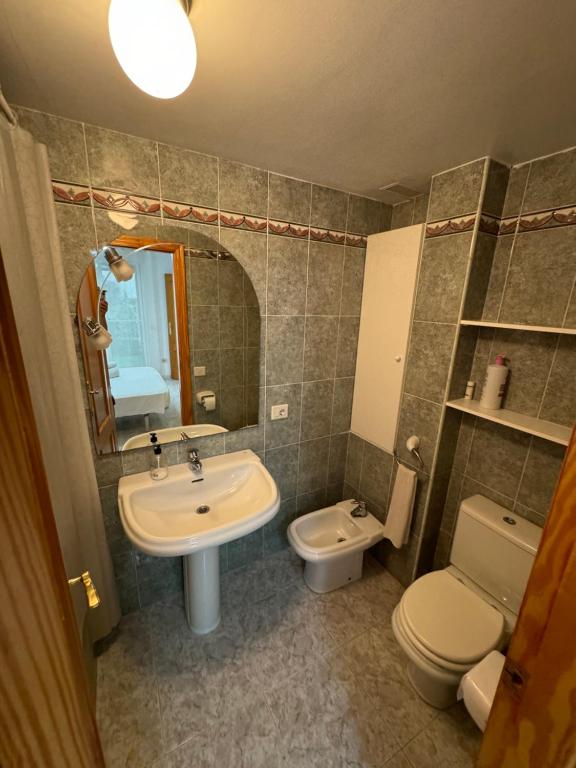 un bagno con lavandino, WC e specchio di Apto 3 habitaciones, vistas al mar Moncofar Grao a Moncófar
