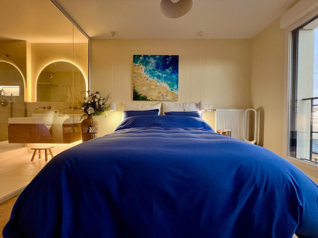 - une chambre avec un lit bleu et une salle de bains dans l'établissement Duplex vue Montmartre lumineux et design épuré, à Saint-Ouen