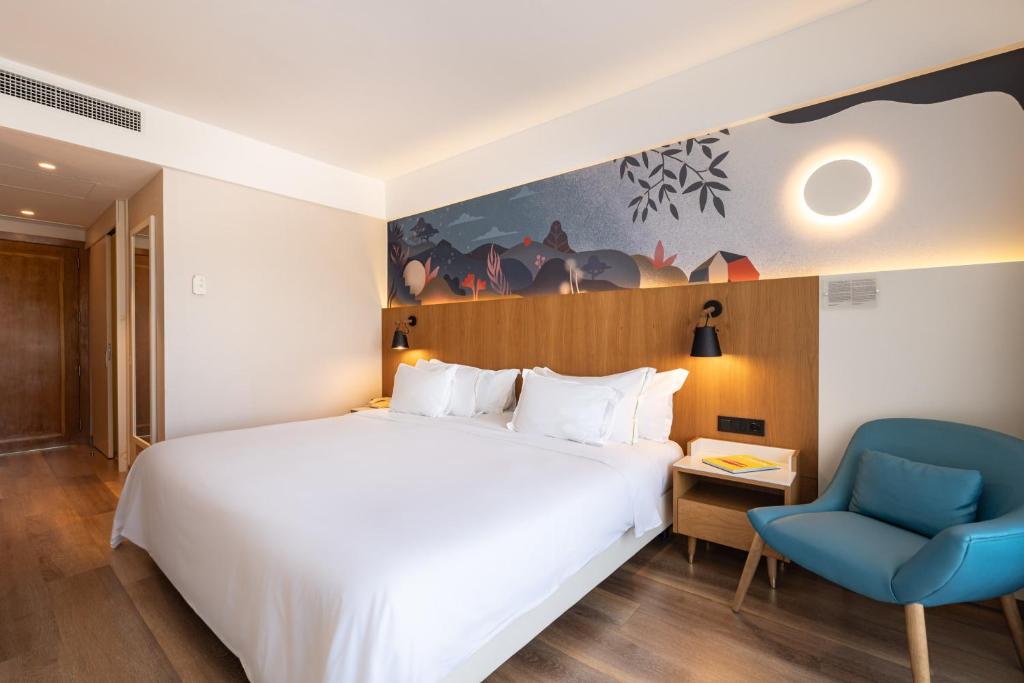 a bedroom with a white bed and a blue chair at Onyria Quinta da Marinha Hotel in Cascais