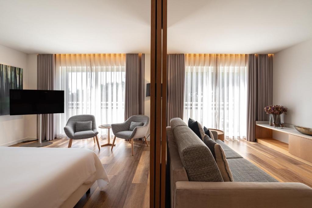 a hotel room with a bed and a couch and chairs at Onyria Quinta da Marinha Hotel in Cascais