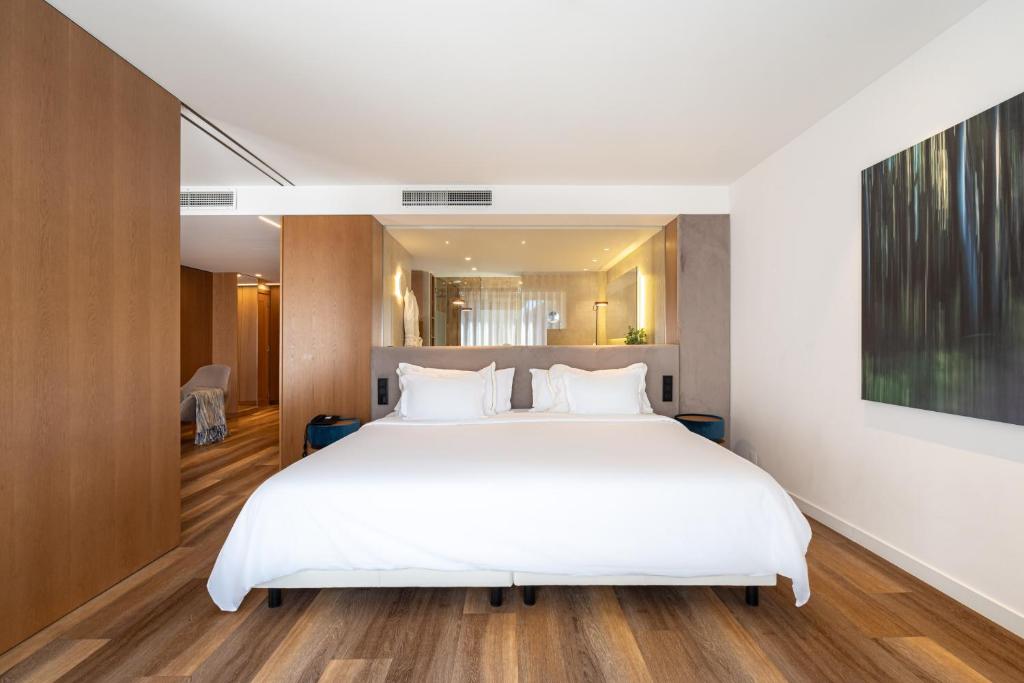 a bedroom with a large white bed and wooden floors at Onyria Quinta da Marinha Hotel in Cascais
