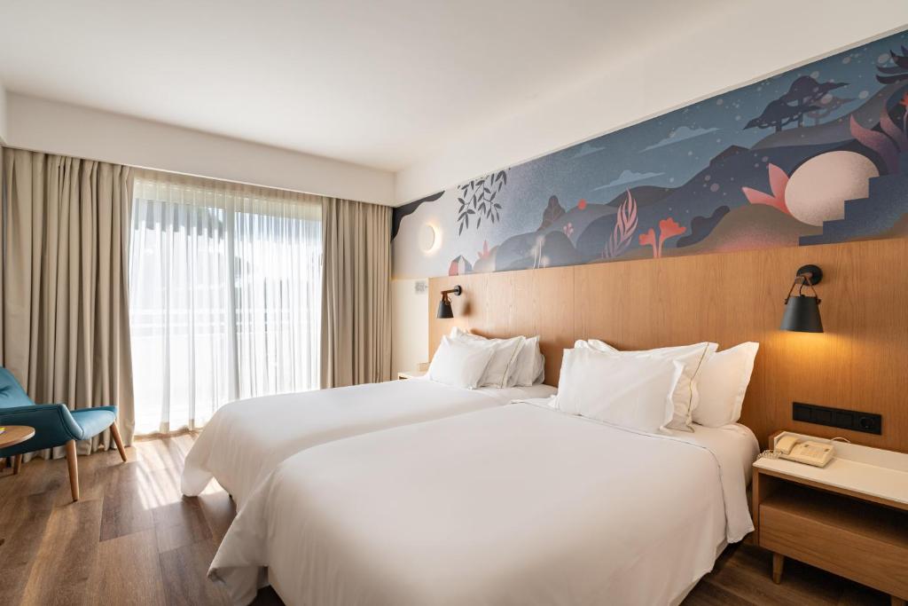 a hotel room with two white beds and a desk at Onyria Quinta da Marinha Hotel in Cascais