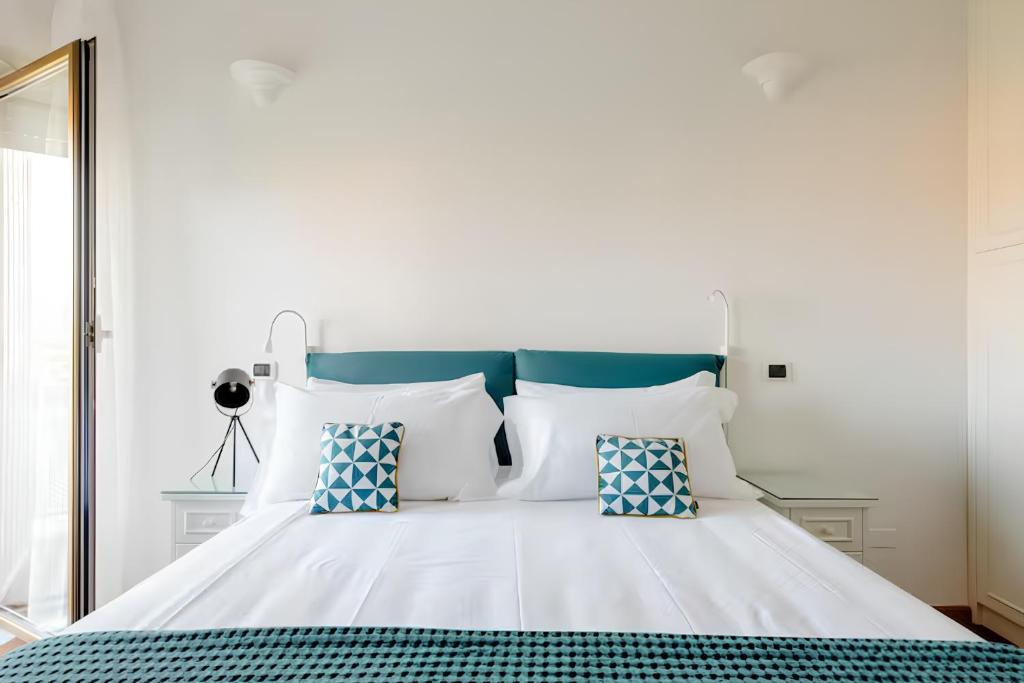 a white bed with blue and white pillows and a mirror at Nonna Cocchina House Rome close to Vatican City in Rome