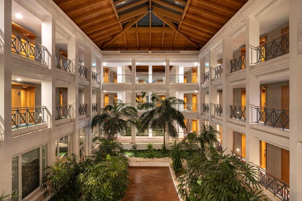 an indoor courtyard with palm trees in a building at Onyria Quinta da Marinha Hotel in Cascais