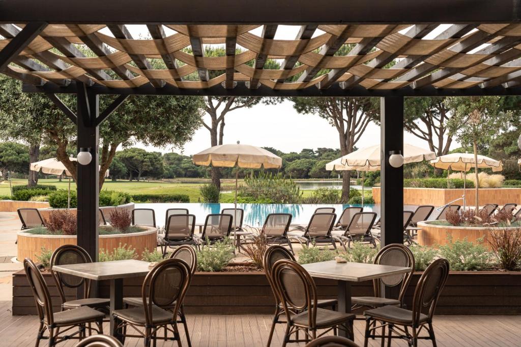 a patio with tables and chairs and a pool at Onyria Quinta da Marinha Hotel in Cascais