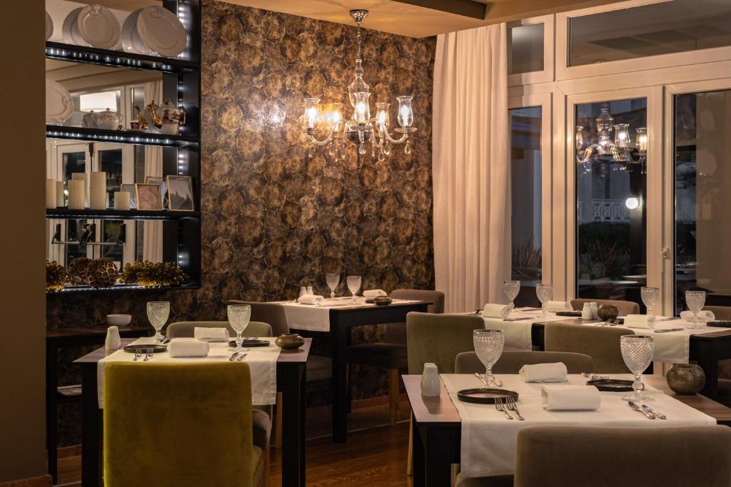 a restaurant with white tables and chairs and a chandelier at Onyria Quinta da Marinha Hotel in Cascais