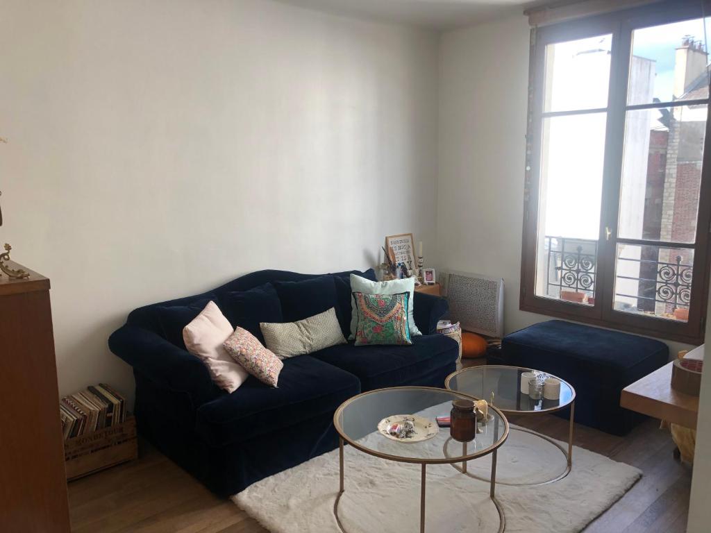 un salon avec un canapé bleu et deux tables dans l'établissement Appartement chaleureux proche Paris, à Montrouge