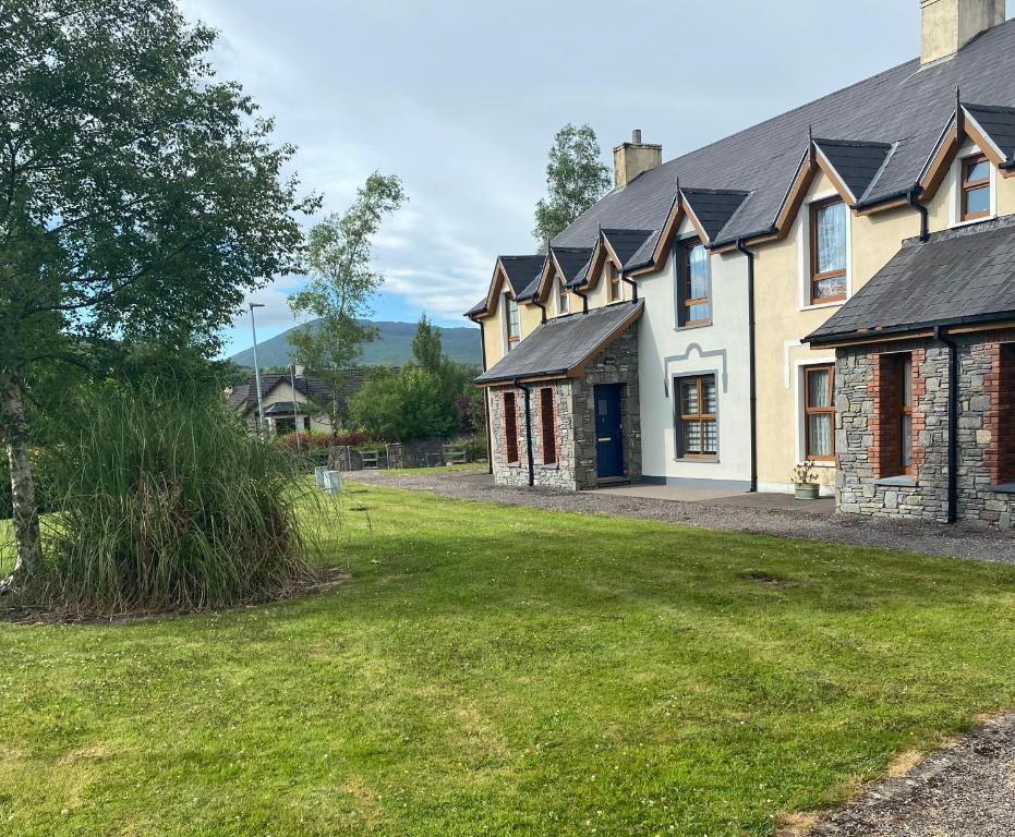 une maison avec une cour d'herbe devant elle dans l'établissement Kenmare Holiday Cottage, à Kenmare