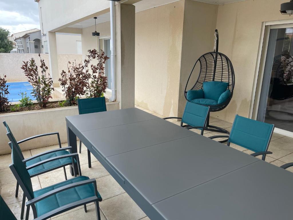- une table et des chaises sur une terrasse avec une balançoire dans l'établissement Bienvenue à la Casa Familia !, à Sérignan