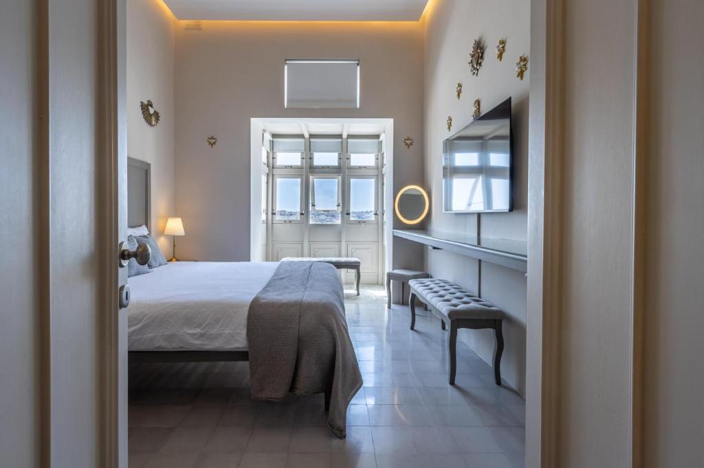 a bedroom with a bed and a chair and a window at Stylish Seaview Valletta House in Valletta