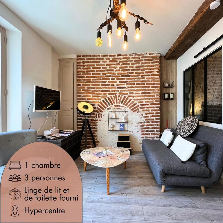 un salon avec un canapé et un mur de briques dans l'établissement Côté Médicis - Cosy appartement au coeur de Blois, à Blois