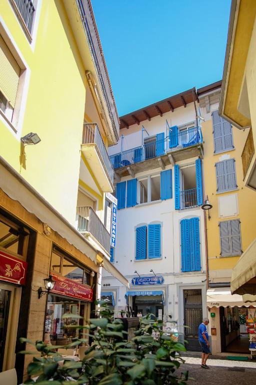 a building with blue windows and a person walking in a street at Torre di Londra in Stresa