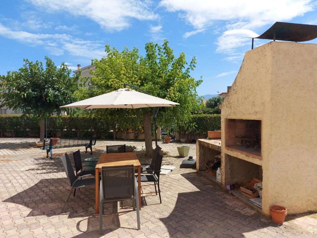 d'une terrasse avec une table, un parasol et une cheminée. dans l'établissement 66m2 ok animaux chéques vacances 2ch wifi 2km mer soleil catalan, à Latour-Bas-Elne