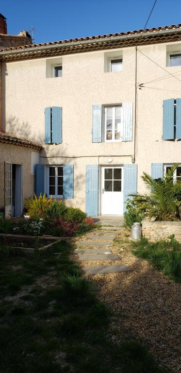 un bâtiment avec des fenêtres à volets bleus et une allée dans l'établissement VELO VENTOUX et NESQUE, à Villes-sur-Auzon