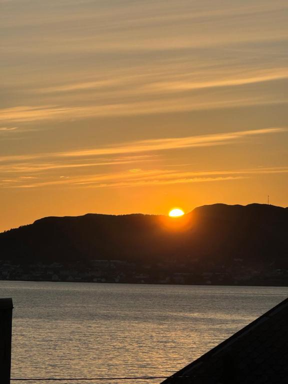 un coucher de soleil sur l'eau avec des montagnes en arrière-plan dans l'établissement Ålesund sentrum apartment, à Ålesund
