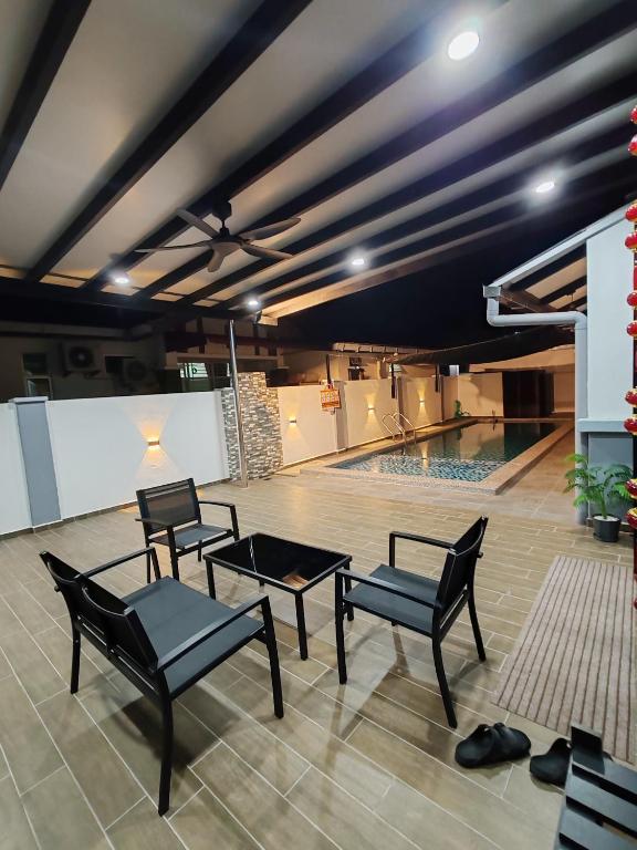 a pool room with chairs and a table and a pool at Melaka privatepool bungalow BBQWIFI krubong in Melaka
