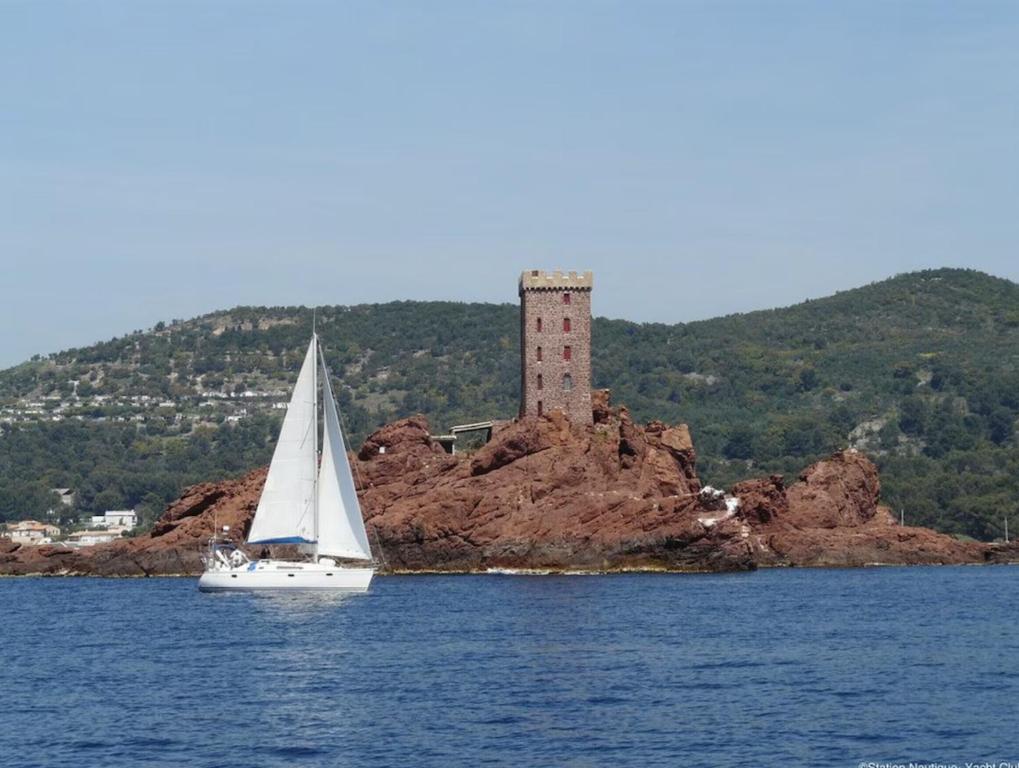 un voilier dans l'eau avec un phare dans l'établissement Appartement biaritz, à Saint-Raphaël