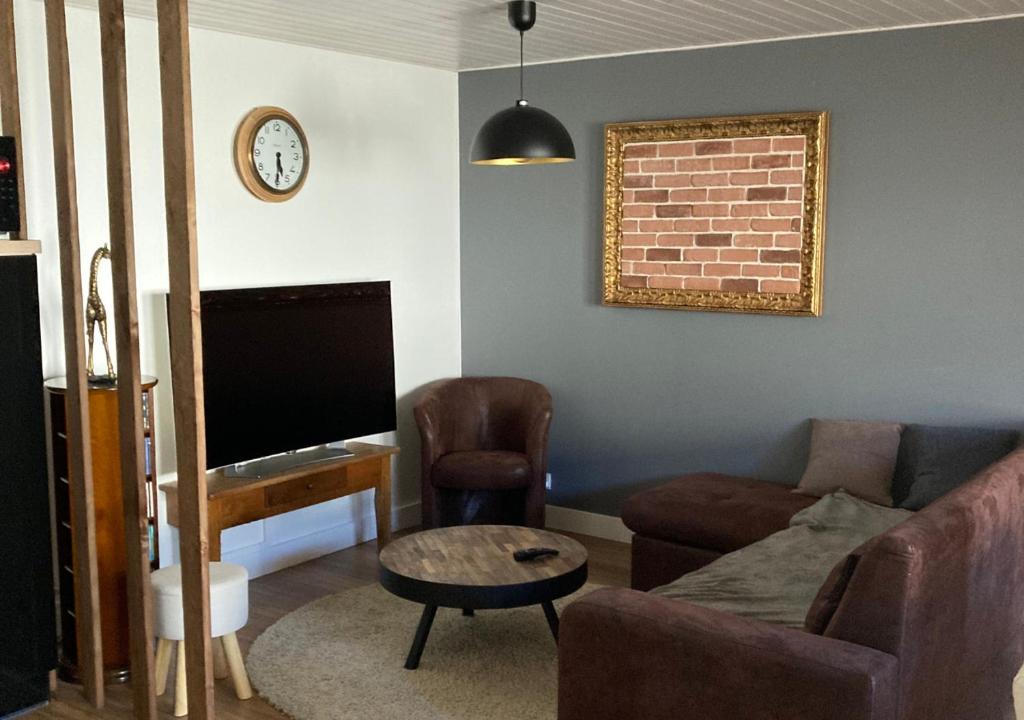 a living room with a couch a chair and a tv at Entre terre et mer in Les Essarts